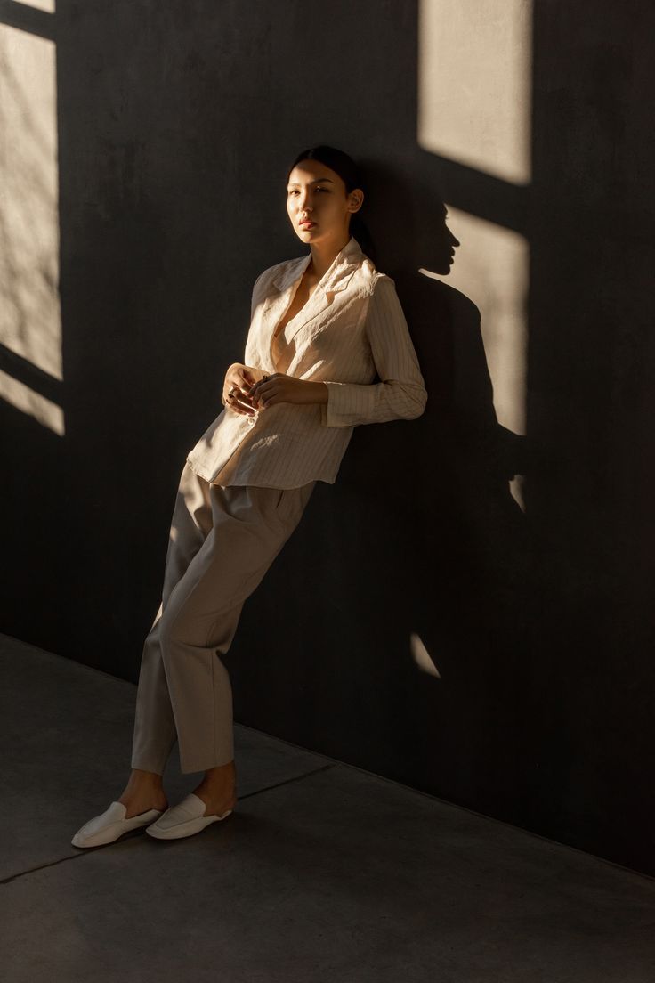 Model leaning against the wall with soft touches of light on her