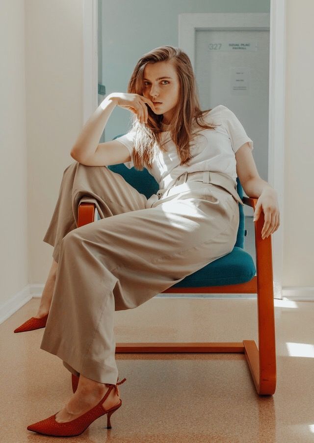 Woman casually sitting on a chair with one leg propped on the ledge