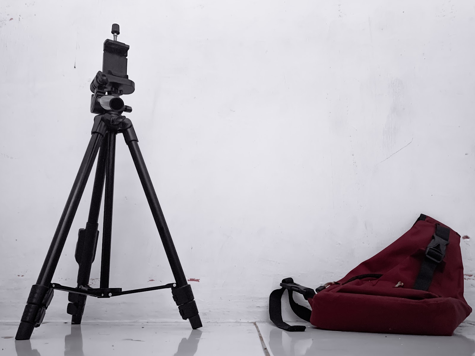 Black tripod with red backpack beside