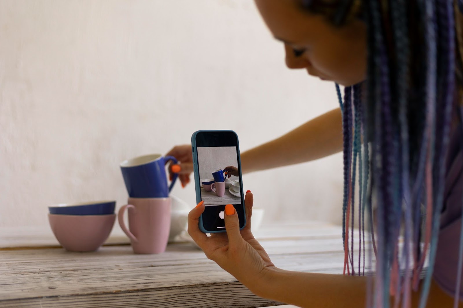 Photographer taking photos of ceramic cups with her mobile phone