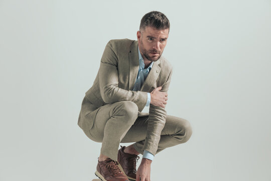 Man crouching in beige suit